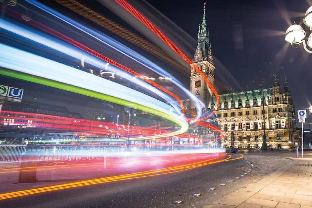 Hamburger Rathaus bei Nacht mit Lichtstreifen von Fahrzeugen
